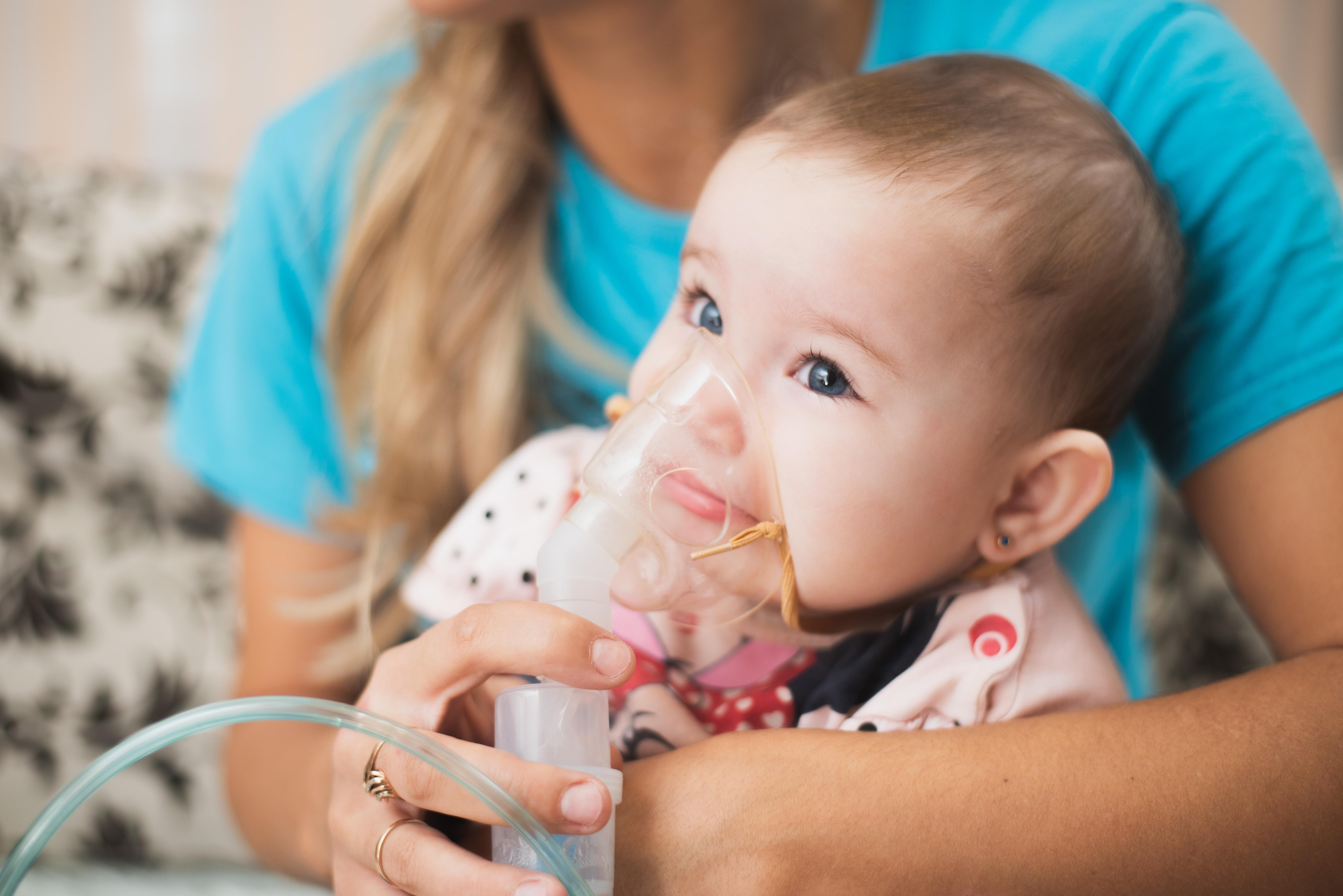 Eine Frau hält ein Baby mit einem Inhalator